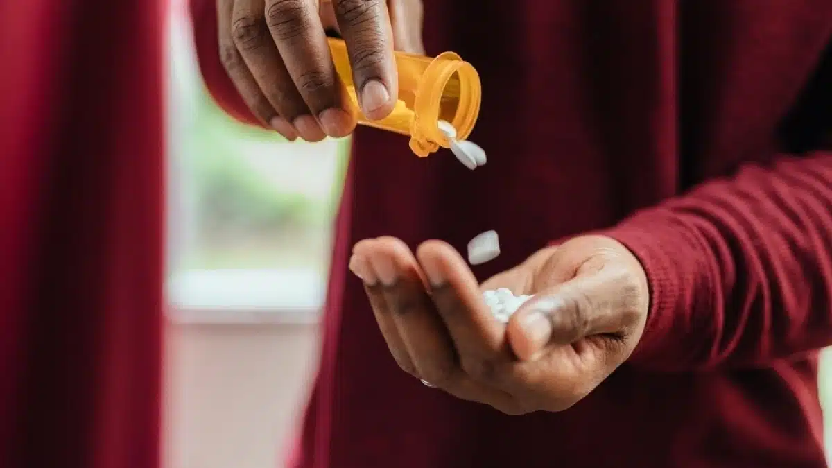 Woman pouring pills out of a bottle into her hand. Graphic lists treatment options for opioid addiction including residential treatment and therapy.