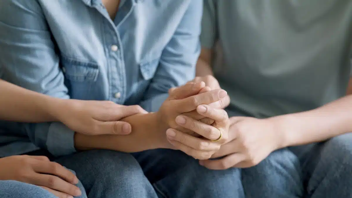Adults in family therapy holding hands in support. Family support helps individuals stay on the path to recovery.