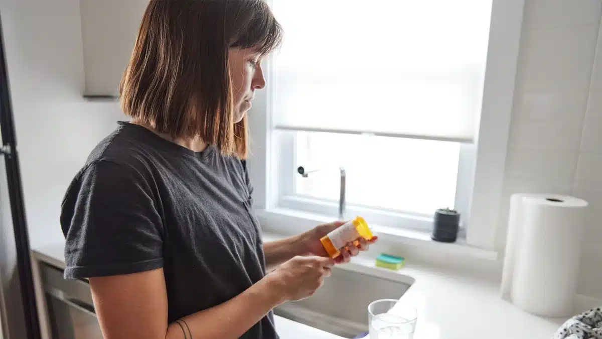 Teen holding a pill bottle of adderall near a glass of water. Abruptly stopping adderall use can lead to adderall withdrawal.