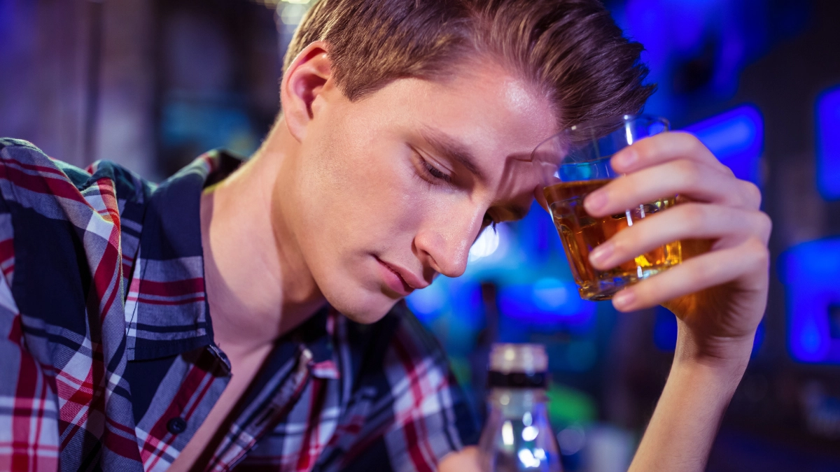 distressed teen with a glass of alcohol in his hand