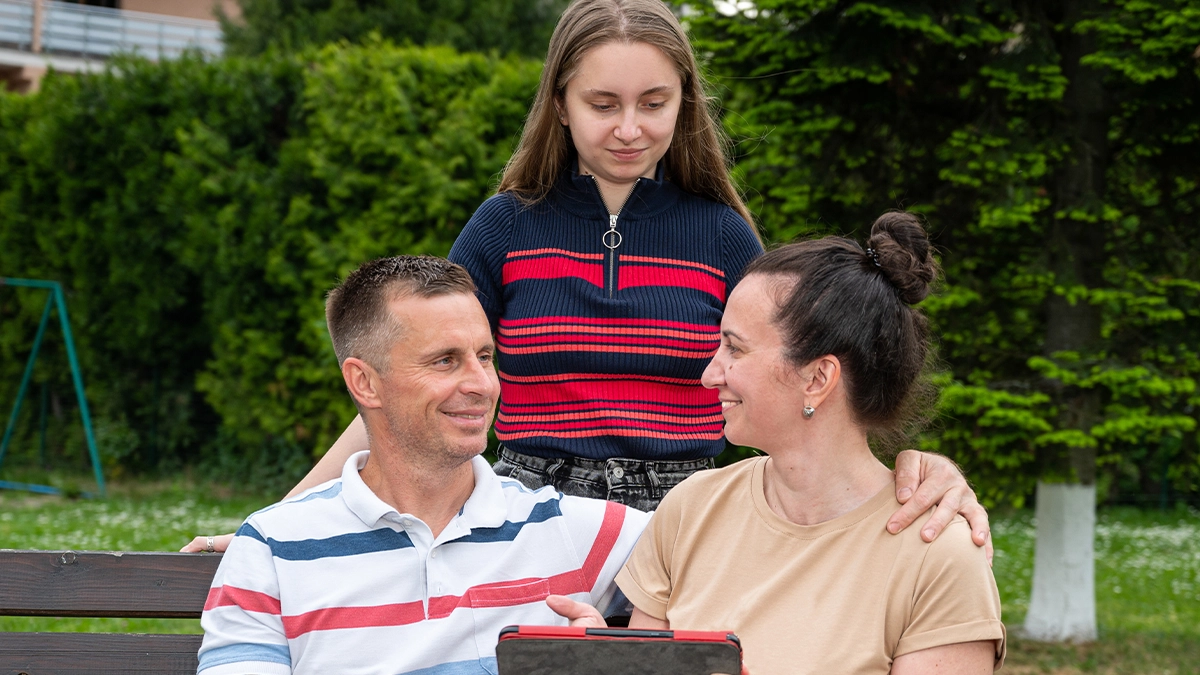 parents sitting on a bench with their child standing behind them