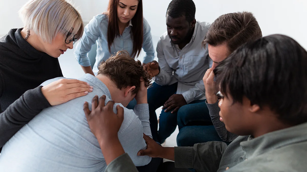 A diverse group of young people engaged in a supportive counseling session.